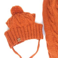 an orange knitted hat and scarf laying next to each other