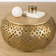 a gold coffee table with a white ball on top and a book in the middle