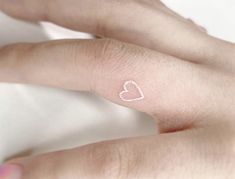 a person with a small heart tattoo on their finger