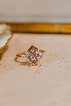 a diamond ring sitting on top of a table next to a flower vase and seashell