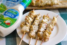 chicken skewers with ranch dressing on a plate next to a bottle of ranch dressing