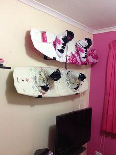 two snowboards mounted to the wall above a tv in a room with pink walls