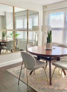 a dining room table with four chairs and a large mirror in the corner behind it