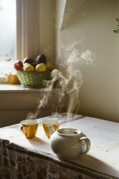 steaming tea on a kitchen counter with fruit in the window sill next to it