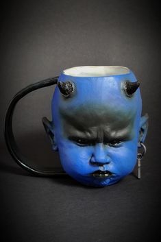 a blue face mug with horns on it's head is shown in front of a black background