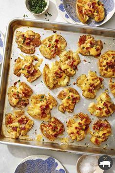 a pan filled with mini pizzas on top of a table next to plates and bowls