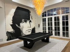 a billiard table in front of a large painting with a man's face on it