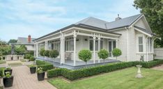 a white house sitting on top of a lush green field next to a garden filled with potted plants