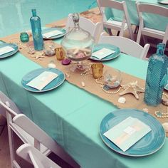 the table is set with blue plates and place settings for an ocean themed dinner party