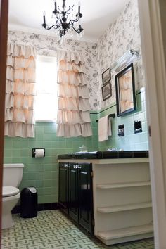 a bathroom with green tiles and white curtains