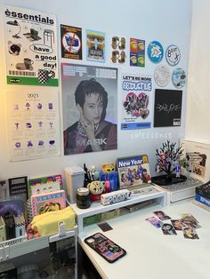 a white desk topped with lots of pictures and magnets next to a laptop computer