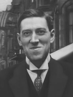 a black and white photo of a man in a suit with a tie on his neck