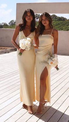 two beautiful women standing next to each other on a wooden floor covered in white flowers