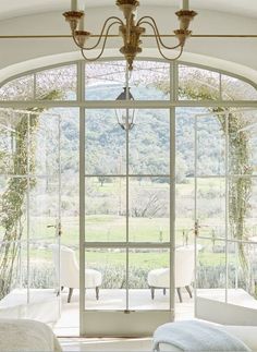 an open window with two chairs and a chandelier hanging from it's ceiling