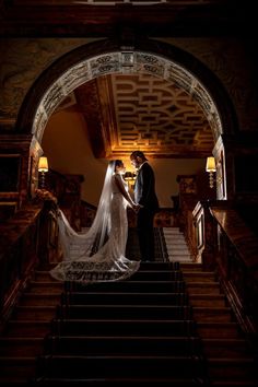 a bride and groom standing on the stairs at their wedding