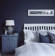 a bedroom with blue walls and white bedding