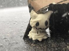 a toy ghost is sitting under an umbrella in the rain, with its head sticking out