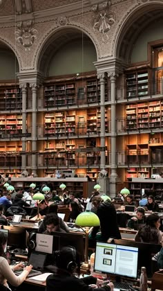 a large library filled with lots of people sitting at desks in front of bookshelves