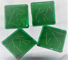 four green square glass coasters with arrows on the top one has an arrow in the middle