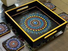 three decorative trays with designs on them sitting on a table next to other items