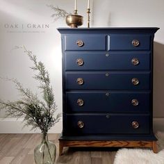 a blue dresser with brass knobs on it and a plant in a vase next to it