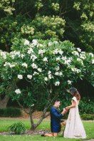 a bride and groom standing in front of a blooming tree