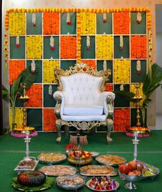 a table topped with lots of food next to a wall covered in orange and yellow tiles