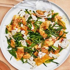 a white plate topped with green beans and croutons next to a wooden spoon