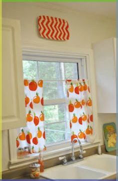 a kitchen with white cabinets and orange curtains