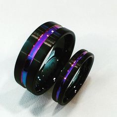 two black ceramic rings with purple and blue lights inlays on each ring, set against a white background