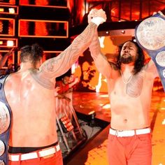 two men are holding up their wrestling belts