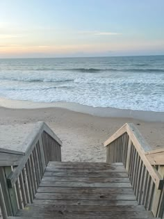 stairs lead down to the beach with waves coming in from the water and sand on either side