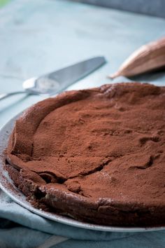 a chocolate cake sitting on top of a white plate next to a knife and fork