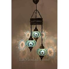 three lights hanging from a chandelier in the shape of balls with blue and white designs