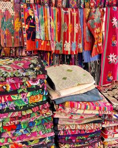 colorful fabrics and scarves for sale at an outdoor market