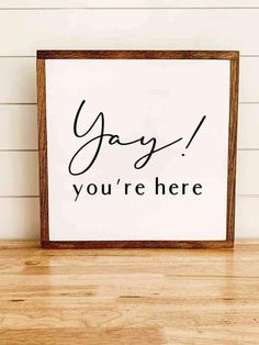 a sign that says yay you're here on the wall next to a wooden table