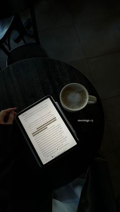 a tablet sitting on top of a table next to a cup of coffee