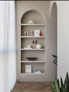 a white shelf with some vases and books on it