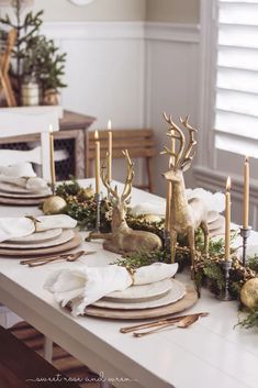 a white table topped with lots of plates and place settings covered in gold antlers