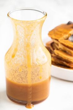 a glass pitcher filled with liquid next to pancakes