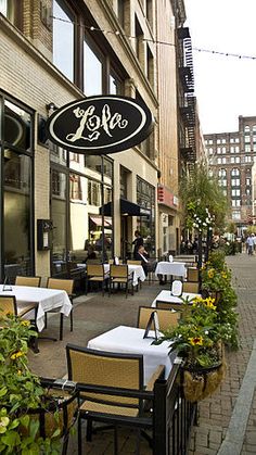 an outdoor restaurant with tables and chairs on the sidewalk