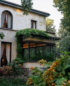 an old building with vines growing on the side and windows above it is surrounded by greenery