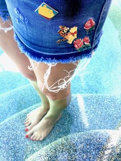 a woman's bare feet wearing blue jeans with winnie the pooh patches on them