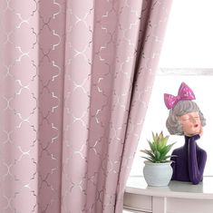 a doll is sitting on a table next to a potted plant and window curtain