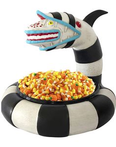 an animal statue with corn in it's mouth and a bowl full of candy