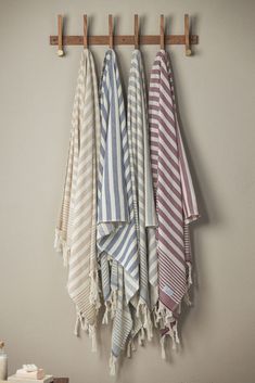 three towels hanging on a wooden rack in a bathroom