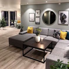 a living room with grey couches and yellow pillows