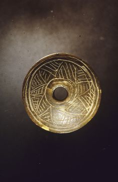 a gold plate with an intricate design on the top and bottom, sitting on a black surface