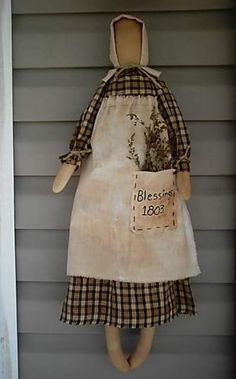 an old fashioned doll is hanging from the side of a house with a sign on it