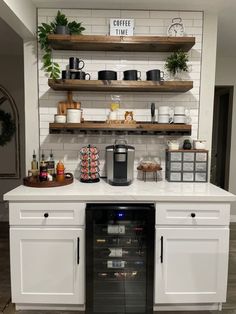 a kitchen with white cabinets and open shelving above the stove is filled with coffee